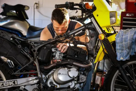 Mekanik sedang menerapkan cara mengatasi mesin motor sering mogok di bengkel