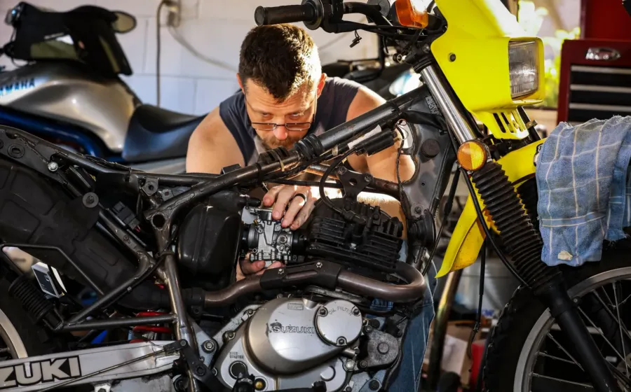Mekanik sedang menerapkan cara mengatasi mesin motor sering mogok di bengkel