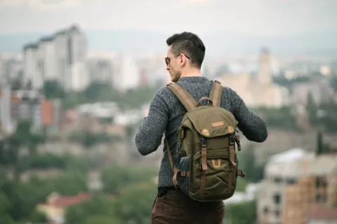 Seorang petualang wanita memperagakan cara traveling solo aman saat menjelajahi kota asing dengan backpack