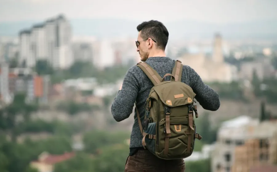 Seorang petualang wanita memperagakan cara traveling solo aman saat menjelajahi kota asing dengan backpack