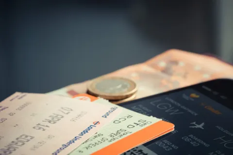 Ilustrasi mencari tiket pesawat murah lewat aplikasi di smartphone saat merencanakan liburan hemat