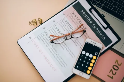 Ilustrasi strategi harga jual produk menggunakan kalkulator dan catatan modal dagangan
