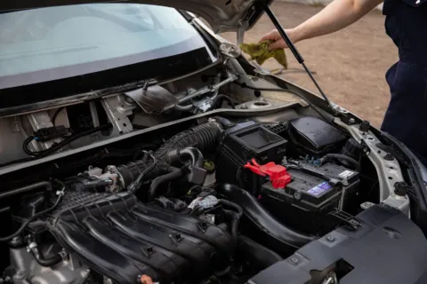 Mekanik sedang mengecek cara merawat aki mobil agar awet dan bebas tekor di bengkel
