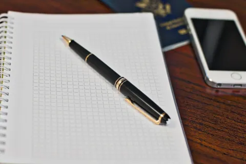 Buku jurnal dan pulpen di atas meja untuk menerapkan ide journaling untuk pemula yang fungsional