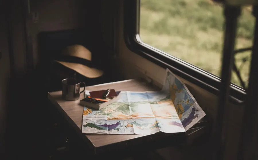 Ilustrasi menyusun itinerary perjalanan liburan dengan peta digital dan catatan rencana perjalanan di kafe