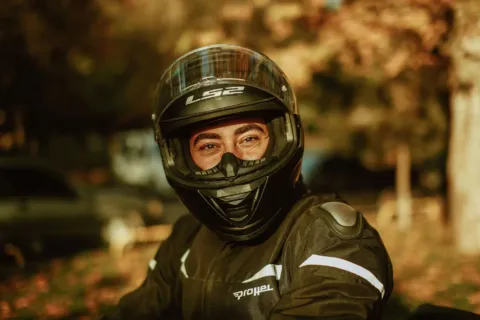Pengendara motor sedang mempraktikkan cara memilih helm yang aman dan nyaman sebelum berkendara di jalan raya