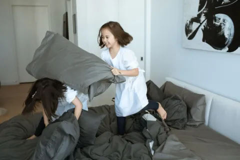 Dua anak kecil sedang berebut mainan di ruang tamu sebagai ilustrasi cara mengatasi sibling rivalry