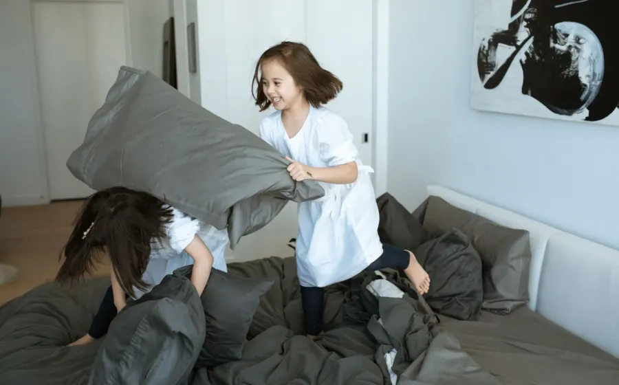 Dua anak kecil sedang berebut mainan di ruang tamu sebagai ilustrasi cara mengatasi sibling rivalry