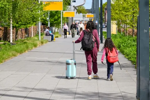 Orang tua dan balita menyiapkan tas kabin saat menerapkan cara traveling dengan anak kecil yang praktis