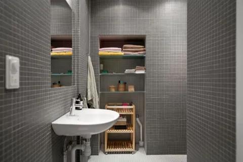 Ide desain kamar mandi minimalis dengan dinding keramik terang dan cermin bulat tanpa bingkai
