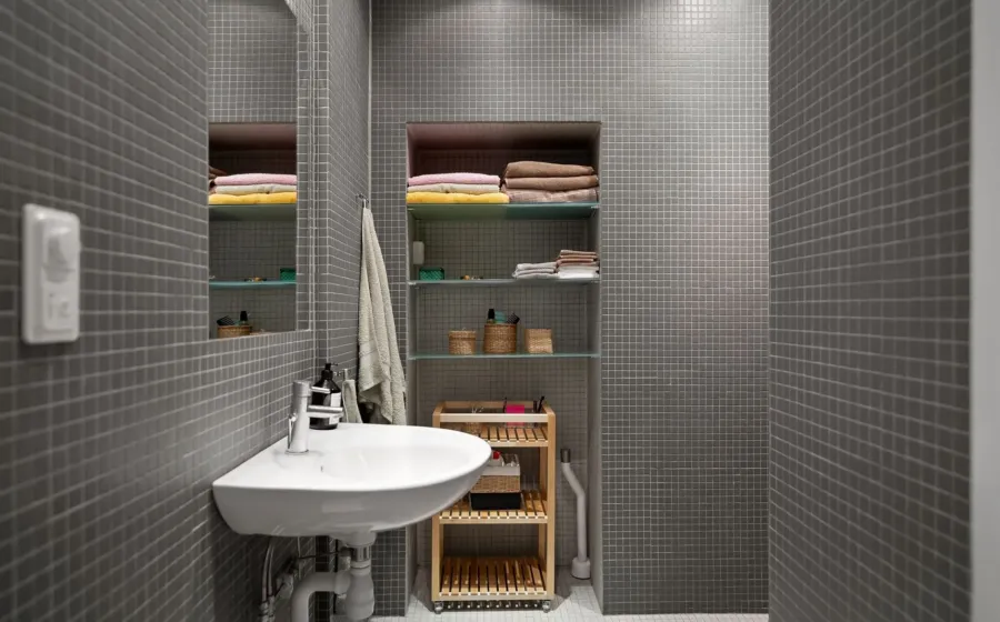 Ide desain kamar mandi minimalis dengan dinding keramik terang dan cermin bulat tanpa bingkai
