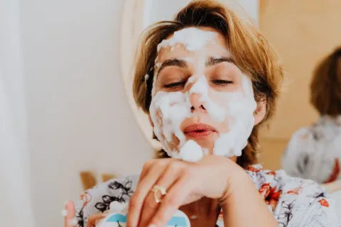 Wanita sedang mengusapkan micellar water ke wajah sebagai tahapan ide double cleansing yang benar