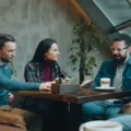 Dua orang sedang mengobrol santai di kedai kopi menerapkan tips bersosialisasi bagi introvert