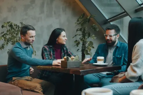 Dua orang sedang mengobrol santai di kedai kopi menerapkan tips bersosialisasi bagi introvert