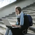 Mahasiswa sedang mengetik tugas kuliah menggunakan laptop fungsional di perpustakaan kampus