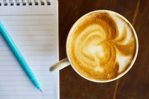 Seseorang menulis ide nama usaha yang menjual di buku catatan saat persiapan merintis bisnis