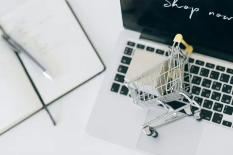 Pelaku usaha sedang mengelola toko pada platform jualan online melalui laptop dan ponsel