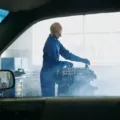 Pengemudi mengecek kap mesin mobil overheat yang mengeluarkan uap di tepi jalan