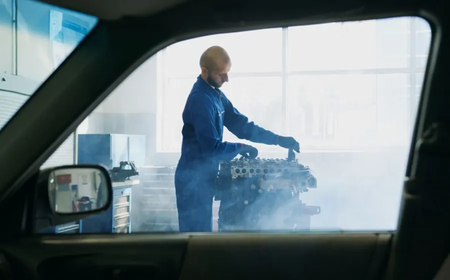 Pengemudi mengecek kap mesin mobil overheat yang mengeluarkan uap di tepi jalan
