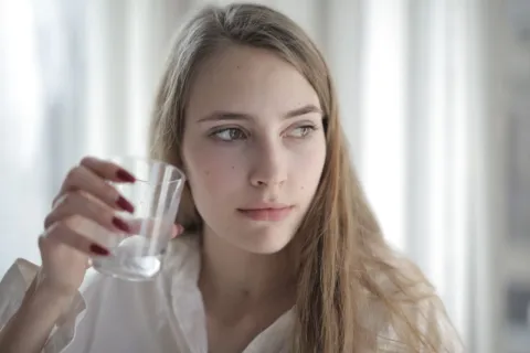 Seseorang sedang minum air segar untuk tips menjaga kesehatan kulit dari dalam